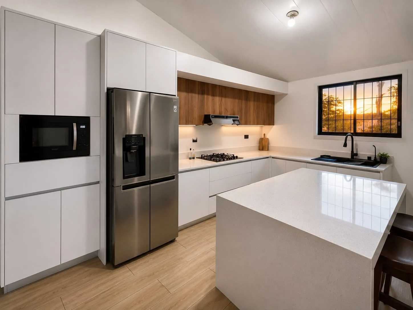 Cocina blanca en U con isla central, gabinetes en madera, ventana amplia y detalles en negro.