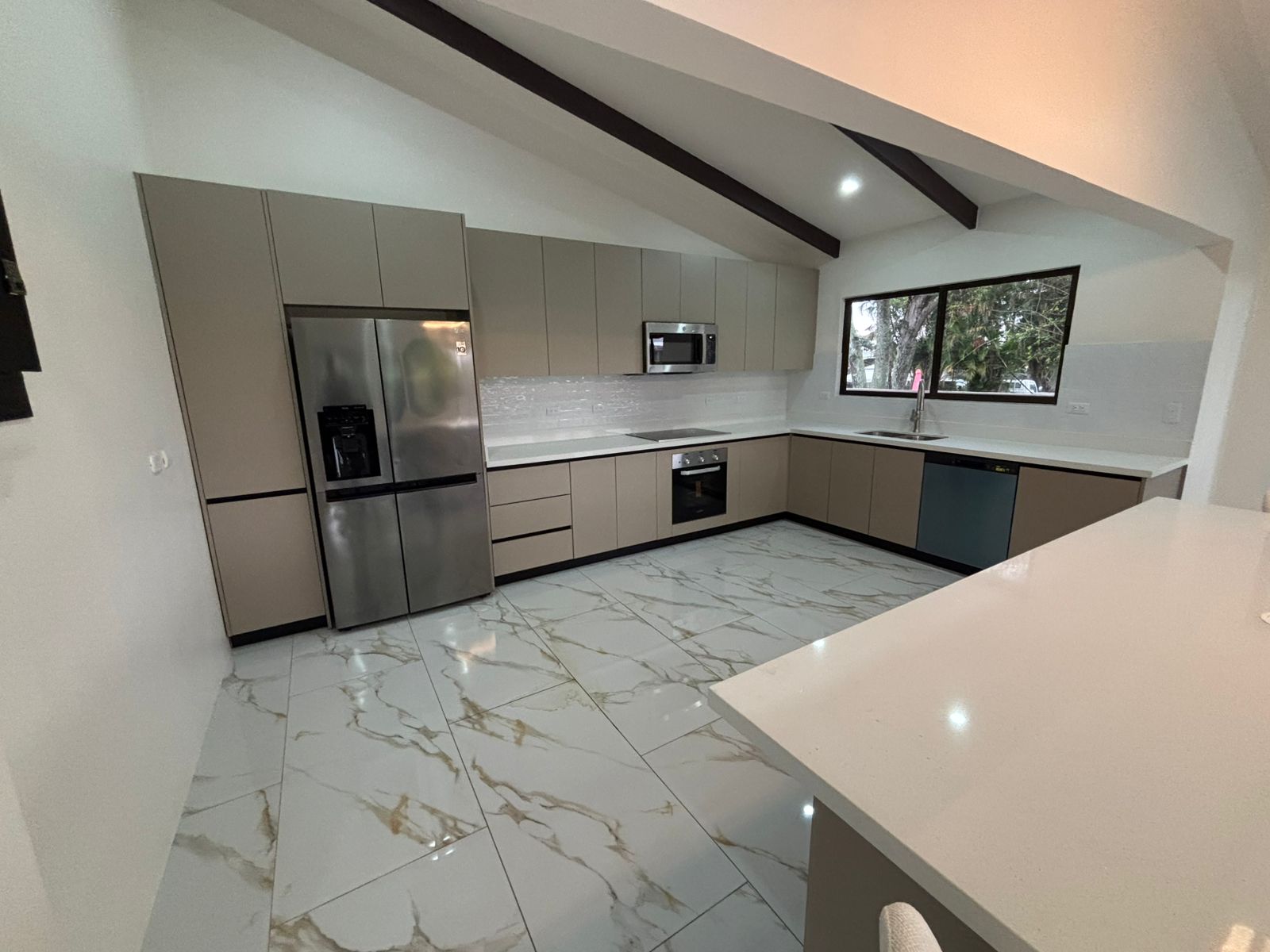 Vista amplia de cocina con isla-comedor central, mobiliario minimalista y superficies blancas continuas.