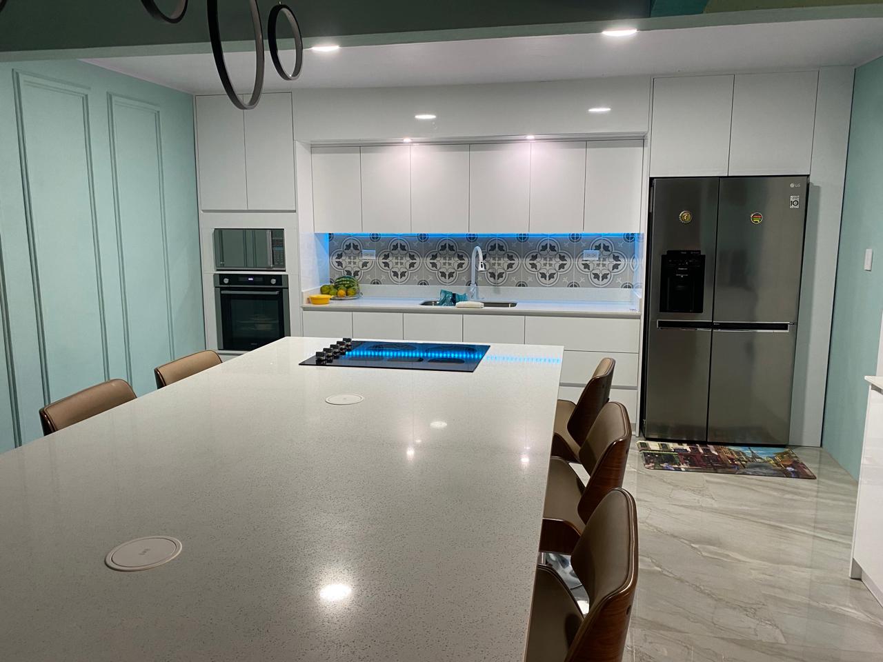 Vista frontal de cocina contemporánea con isla central, sillas altas y cenefa decorativa retroiluminada.